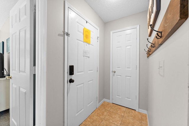 doorway to outside featuring light tile patterned floors and a textured ceiling