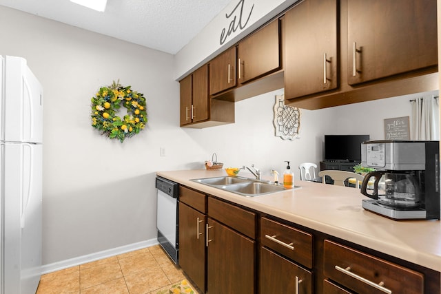 kitchen with white appliances, sink, light tile patterned floors, a textured ceiling, and dark brown cabinetry