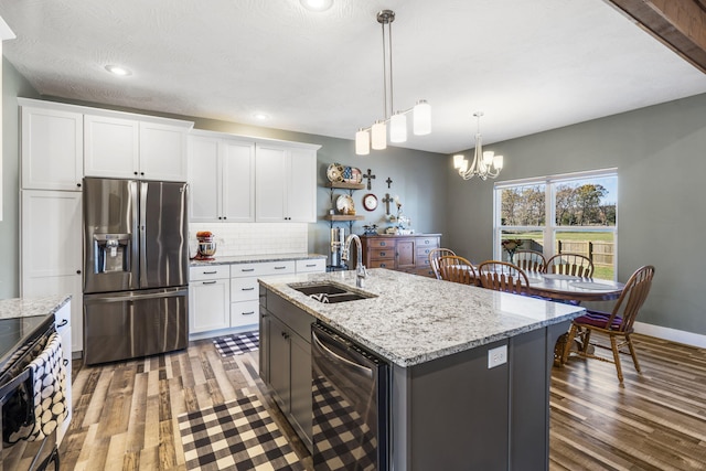 kitchen with hardwood / wood-style floors, stainless steel appliances, white cabinetry, and a center island with sink