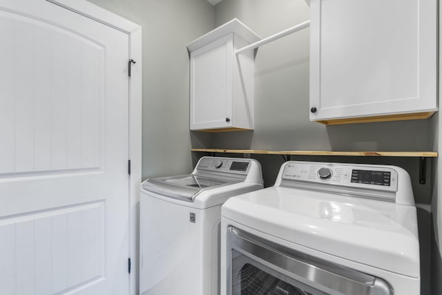 washroom with washing machine and clothes dryer and cabinets