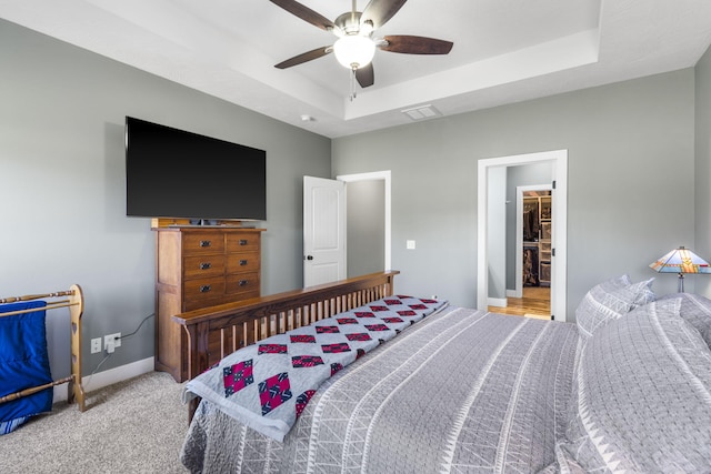 carpeted bedroom with a raised ceiling, ceiling fan, and a spacious closet