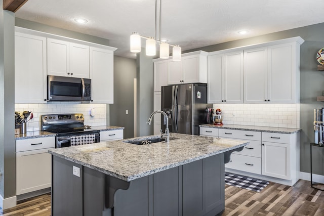 kitchen with white cabinets, an island with sink, stainless steel appliances, and sink