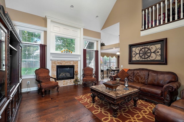 living room with dark hardwood / wood-style flooring, high vaulted ceiling, and a tiled fireplace