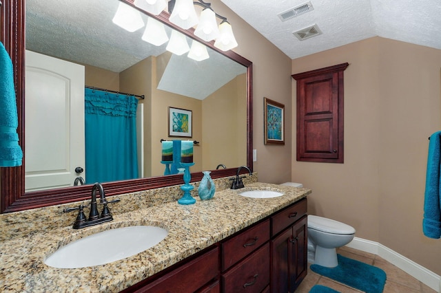 bathroom featuring tile patterned floors, vanity, a textured ceiling, and toilet