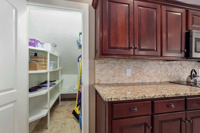 kitchen featuring light stone countertops, backsplash, and black electric cooktop