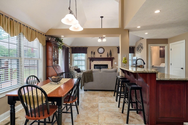 dining room with vaulted ceiling, a healthy amount of sunlight, and a textured ceiling