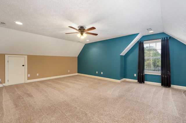 additional living space featuring vaulted ceiling, light carpet, ceiling fan, and a textured ceiling