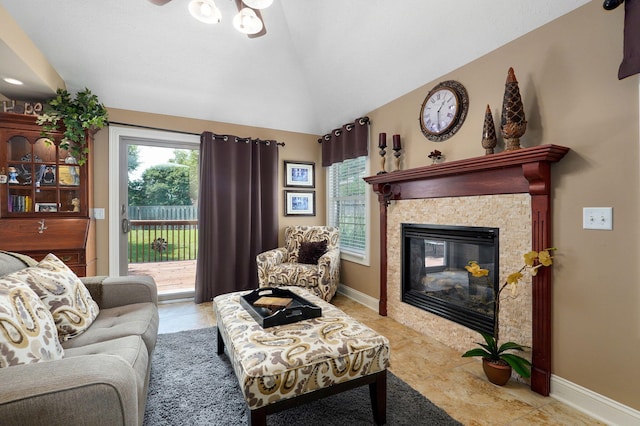 living room with ceiling fan, lofted ceiling, and a fireplace