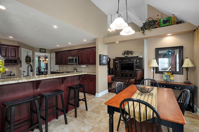 dining space with sink, high vaulted ceiling, a textured ceiling, and an inviting chandelier