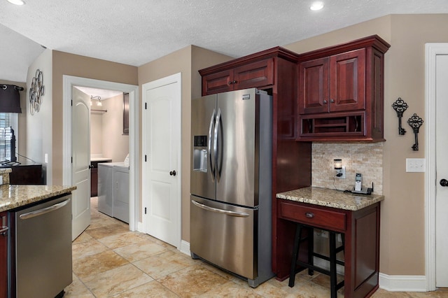 kitchen with separate washer and dryer, light stone countertops, stainless steel appliances, and a textured ceiling