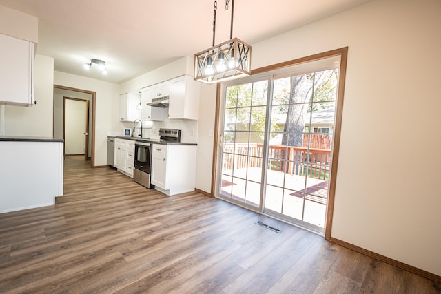 kitchen with white cabinets, wood-type flooring, stainless steel appliances, and hanging light fixtures