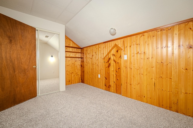 bonus room featuring carpet flooring, wood walls, and vaulted ceiling