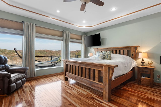 bedroom featuring hardwood / wood-style floors, ceiling fan, and a tray ceiling