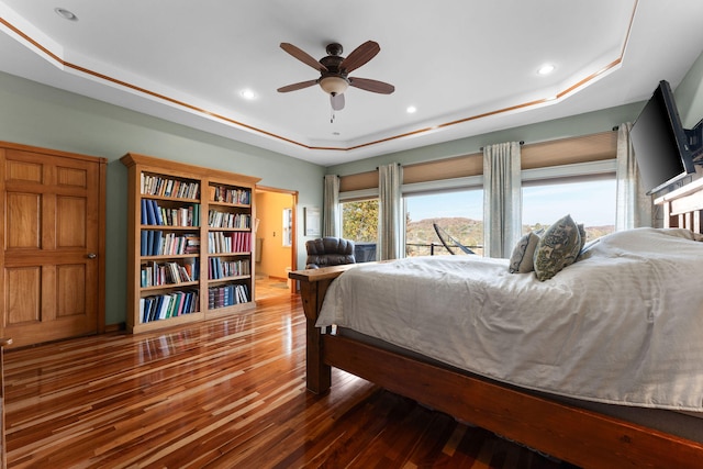 bedroom featuring hardwood / wood-style floors, a tray ceiling, and ceiling fan