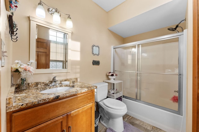 full bathroom with hardwood / wood-style flooring, vanity, toilet, and bath / shower combo with glass door