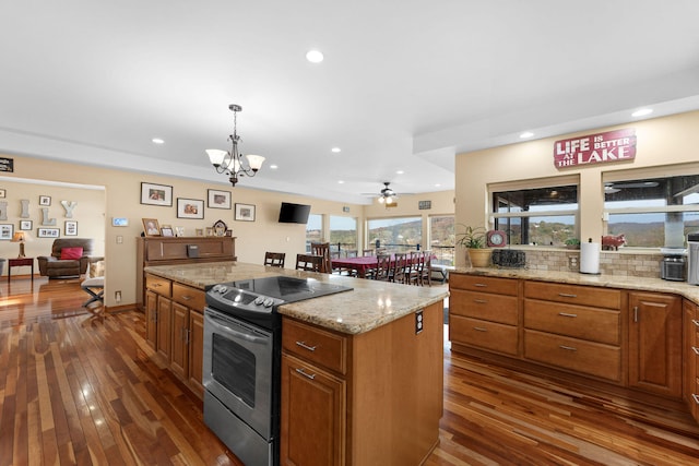 kitchen featuring stainless steel range with electric stovetop, dark wood-type flooring, tasteful backsplash, decorative light fixtures, and a kitchen island