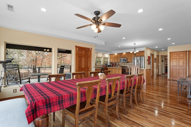 dining room featuring ceiling fan with notable chandelier and light wood-type flooring