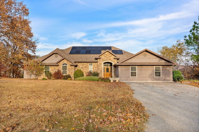 ranch-style house featuring a front lawn and solar panels