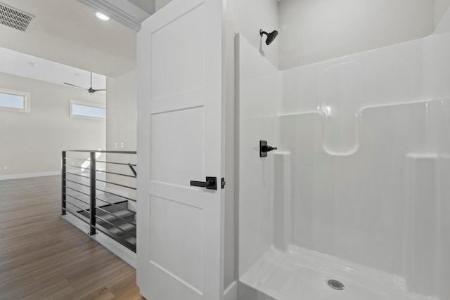 bathroom with ceiling fan, hardwood / wood-style floors, and walk in shower