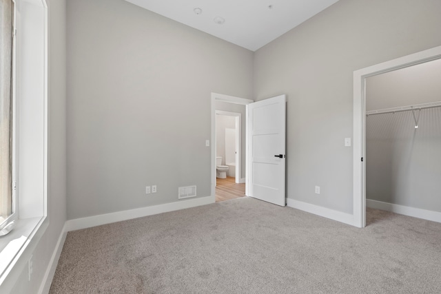 unfurnished bedroom with light colored carpet and a closet