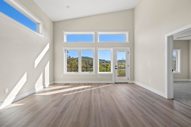 unfurnished living room with high vaulted ceiling and hardwood / wood-style flooring