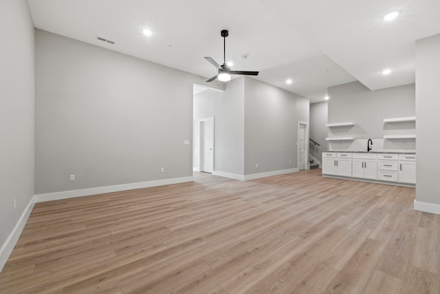 unfurnished living room featuring ceiling fan, sink, and light hardwood / wood-style floors