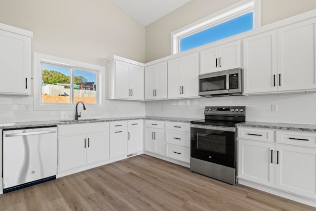 kitchen with sink, white cabinets, stainless steel appliances, and light hardwood / wood-style floors