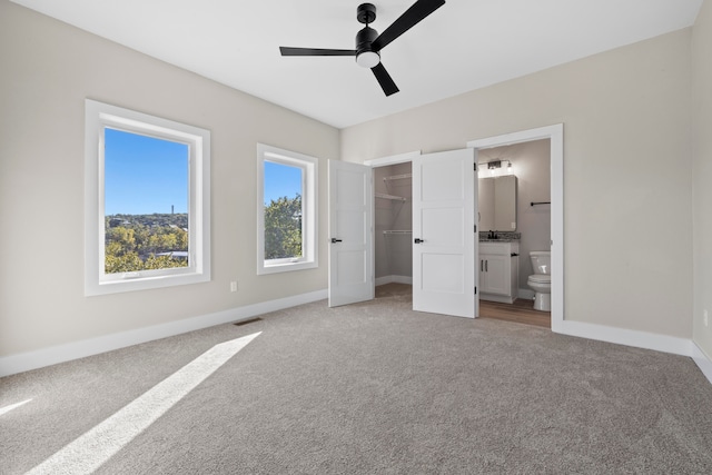 unfurnished bedroom featuring carpet flooring, a walk in closet, ceiling fan, connected bathroom, and a closet