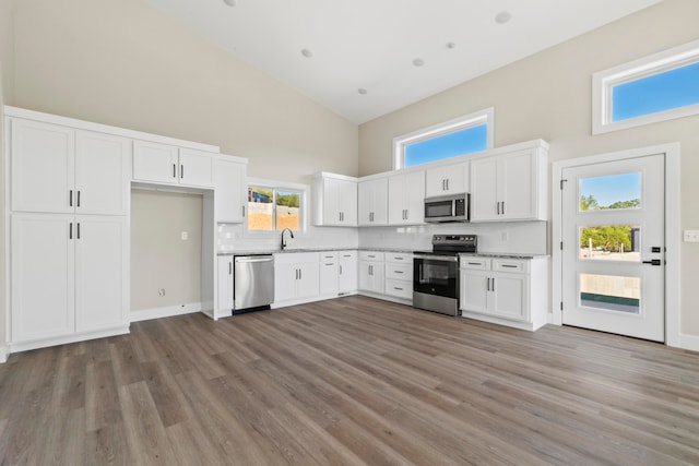 kitchen with high vaulted ceiling, white cabinetry, and appliances with stainless steel finishes