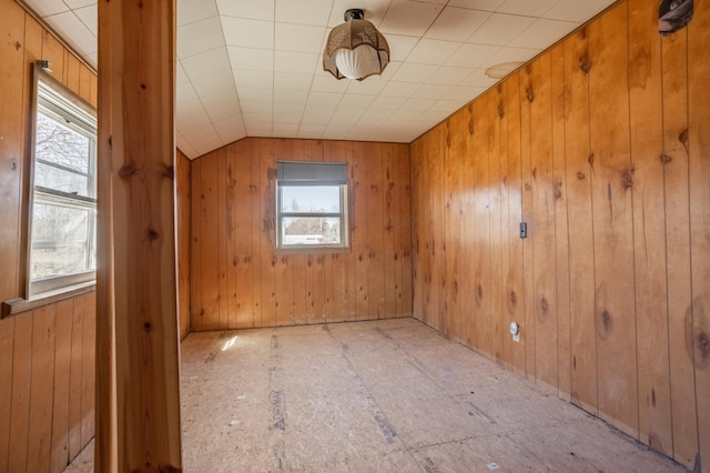 unfurnished room with wood walls and lofted ceiling