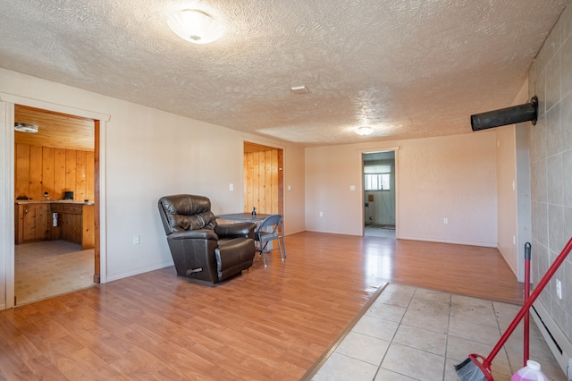 living area featuring baseboard heating, light hardwood / wood-style flooring, and a textured ceiling