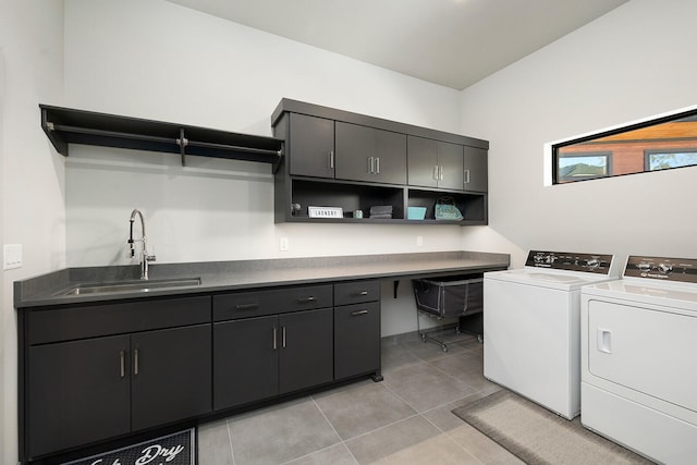 laundry area with washer and clothes dryer, sink, light tile patterned floors, and cabinets