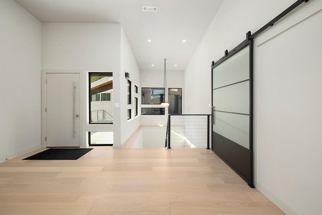 hall with a barn door and light hardwood / wood-style flooring