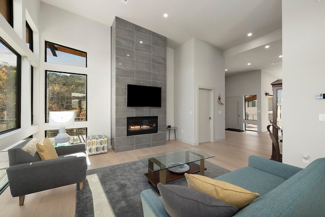 living room featuring a fireplace, a towering ceiling, and light hardwood / wood-style flooring