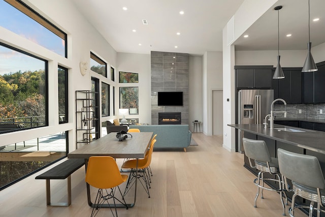 dining space featuring a fireplace, sink, and light hardwood / wood-style flooring