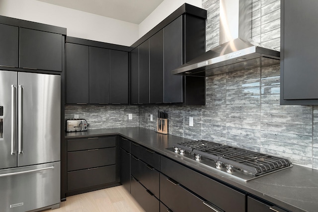 kitchen with decorative backsplash, wall chimney exhaust hood, stainless steel appliances, and light wood-type flooring