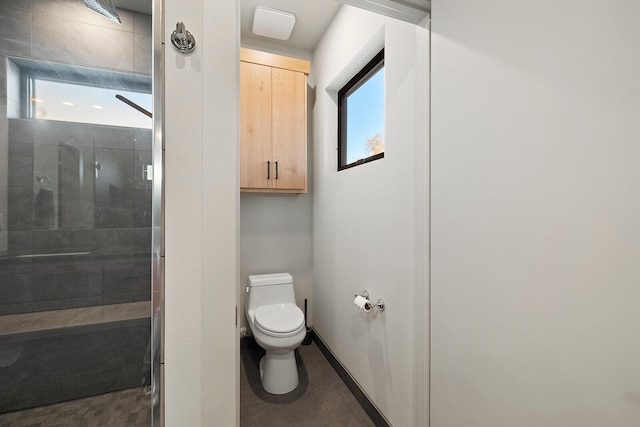 bathroom with tiled shower, plenty of natural light, and toilet