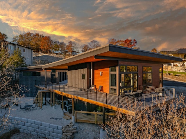 back house at dusk featuring a deck