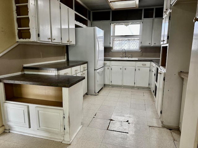 kitchen featuring white fridge, white cabinetry, and sink