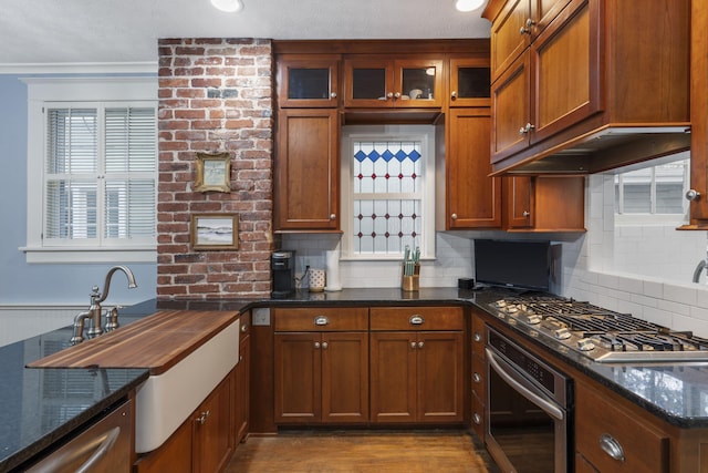 kitchen with appliances with stainless steel finishes, light wood-type flooring, tasteful backsplash, and dark stone counters