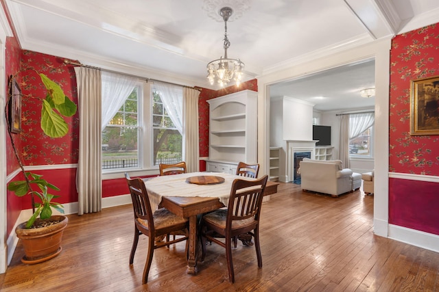 dining area with hardwood / wood-style flooring, an inviting chandelier, and crown molding