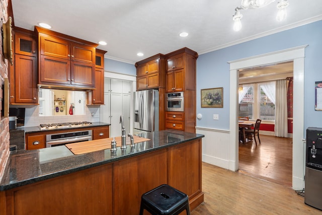 kitchen featuring light hardwood / wood-style floors, dark stone countertops, ornamental molding, and stainless steel appliances