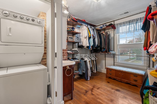 walk in closet featuring light hardwood / wood-style flooring and stacked washer and clothes dryer