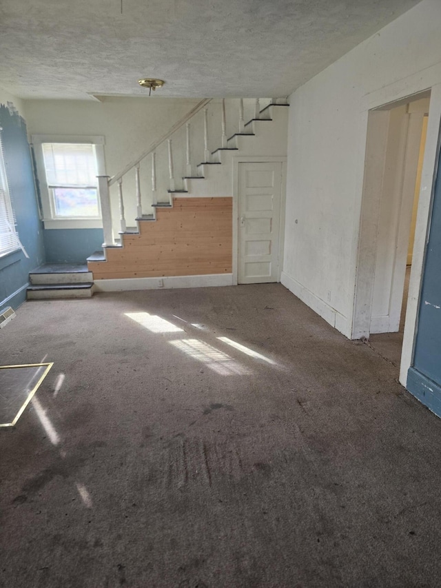 unfurnished living room featuring carpet flooring and a textured ceiling