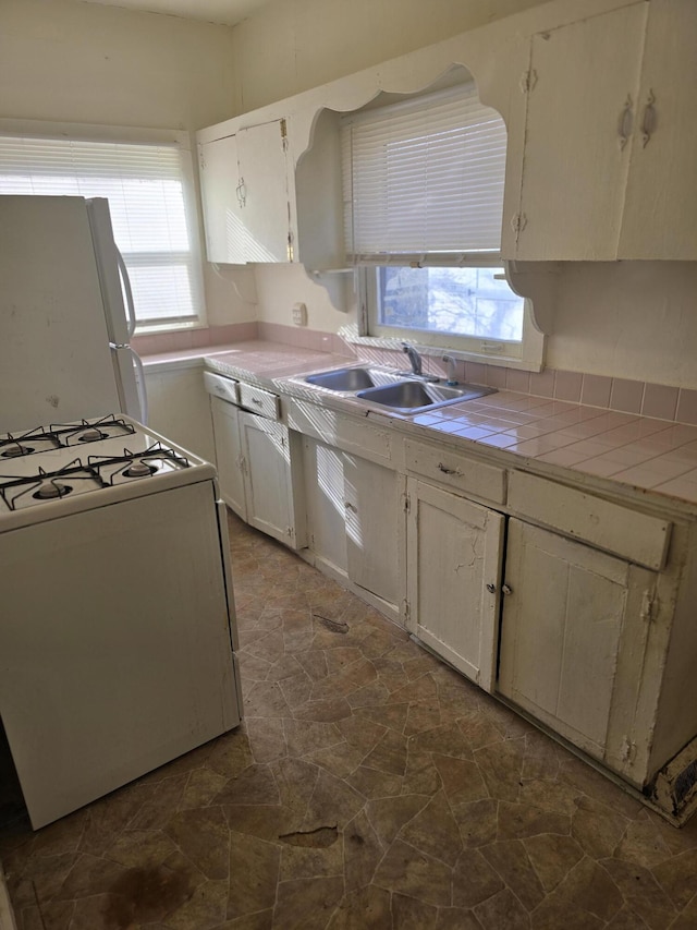 kitchen featuring tile counters, plenty of natural light, white appliances, and sink