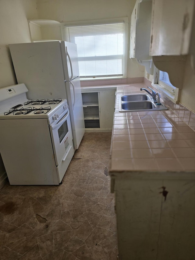 kitchen featuring tile counters, white cabinetry, white range with gas stovetop, and sink