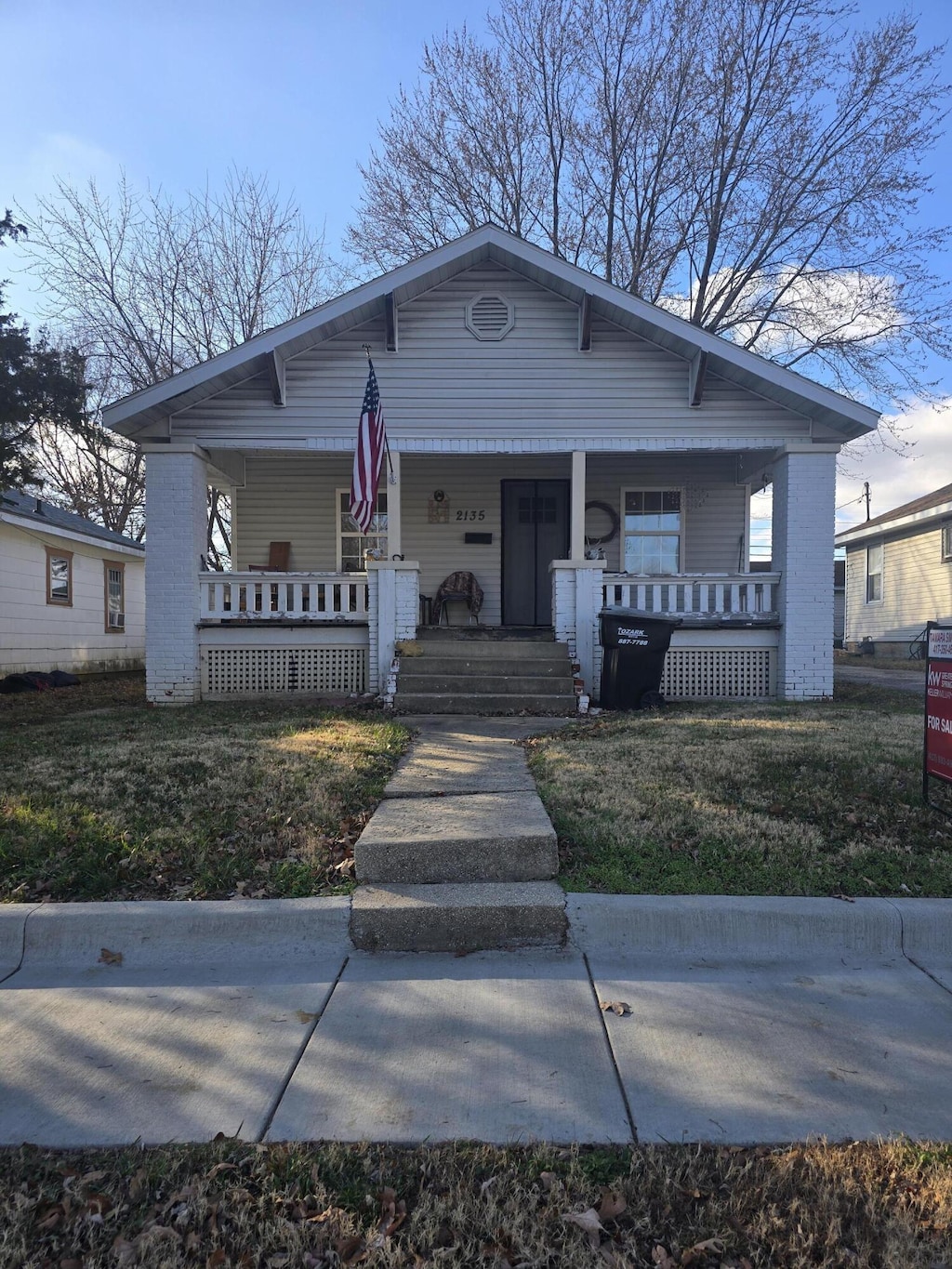 bungalow with a porch and a front lawn