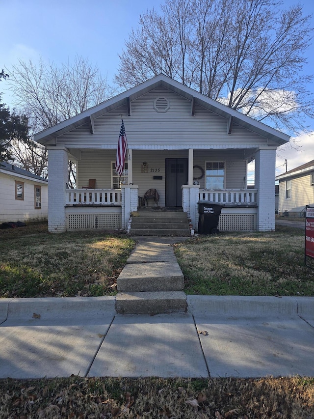 bungalow with a porch and a front lawn