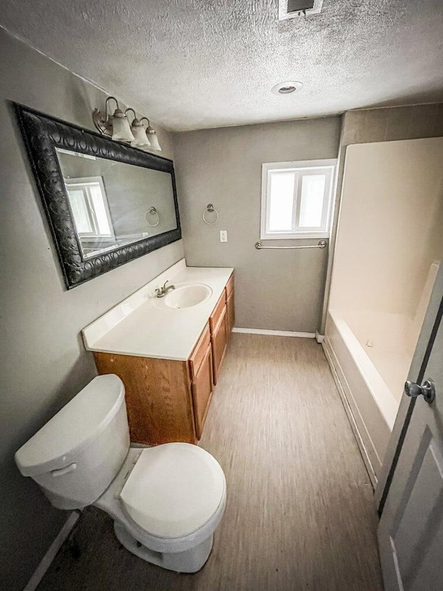 bathroom with walk in shower, wood-type flooring, a textured ceiling, toilet, and vanity