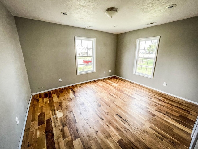 empty room with hardwood / wood-style floors and a healthy amount of sunlight